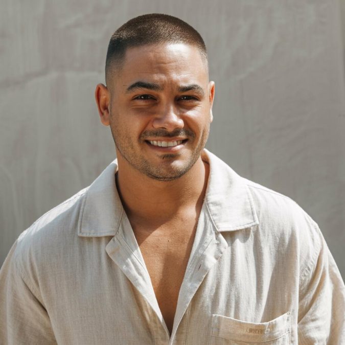 A man with a naturally larger head confidently rocking a short haircut with neat sides