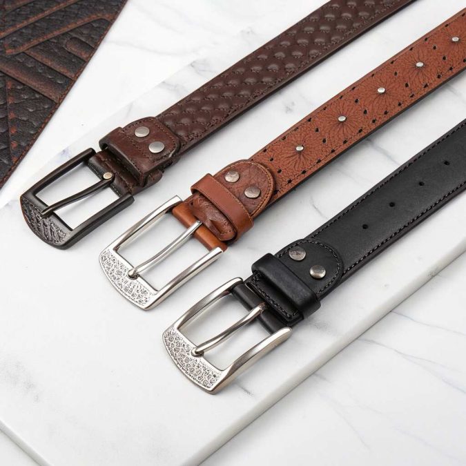 Flat-lay of belt with a buckle, patterned leather belt, and silver black belt variations for men's accessories.