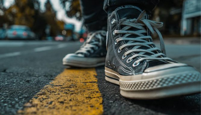A man wearing white leather casual shoes and jeans working in a coffee shop, illustrating the 2026 guide to mastering casual style and comfort.
