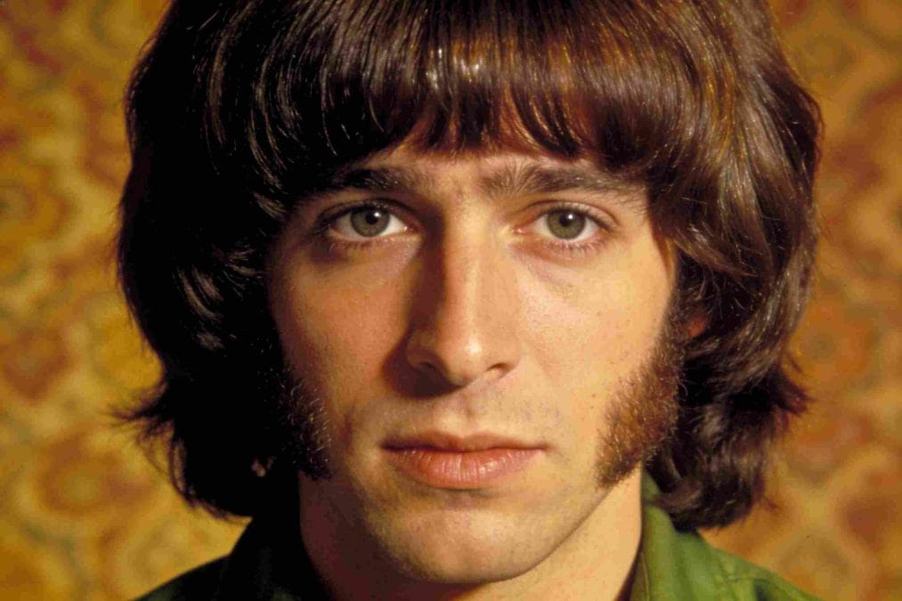 Man with a rounded 70s mop-top hairstyle, full fringe, and long sideburns.