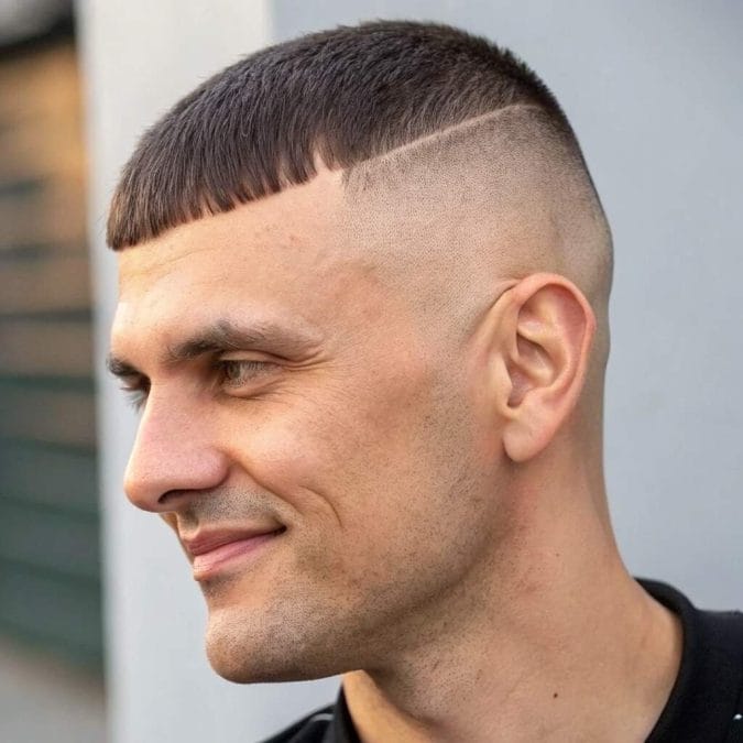 Man with a Caesar cut, short horizontal fringe, and closely faded sides.