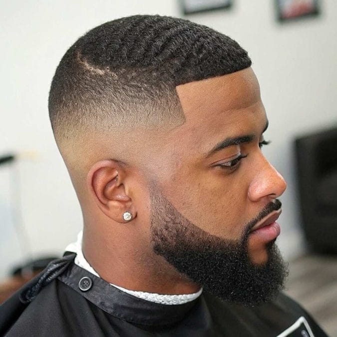 Black man with a clean fade haircut and full beard, demonstrating a modern Haircut Ideas for Black Men look.