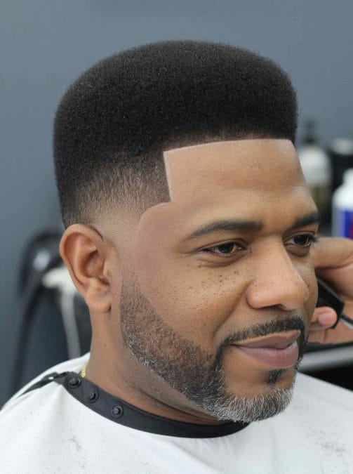 Short Afro taper haircut with clean lineup and beard blend.