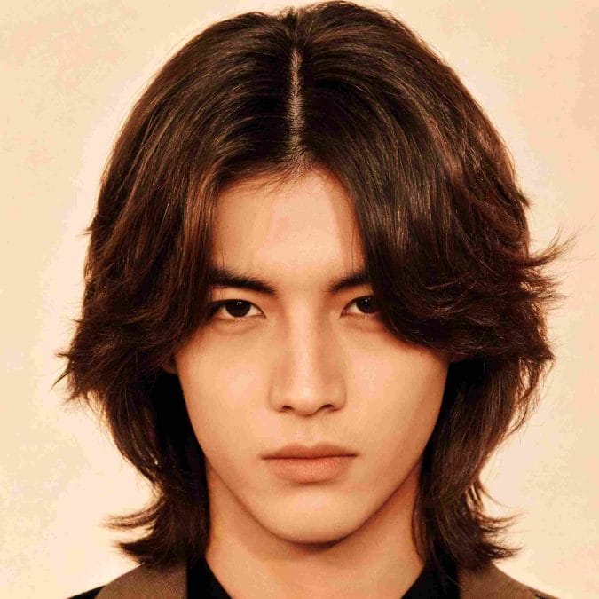 Man with a shoulder-length middle-part hairstyle and softly layered ends.