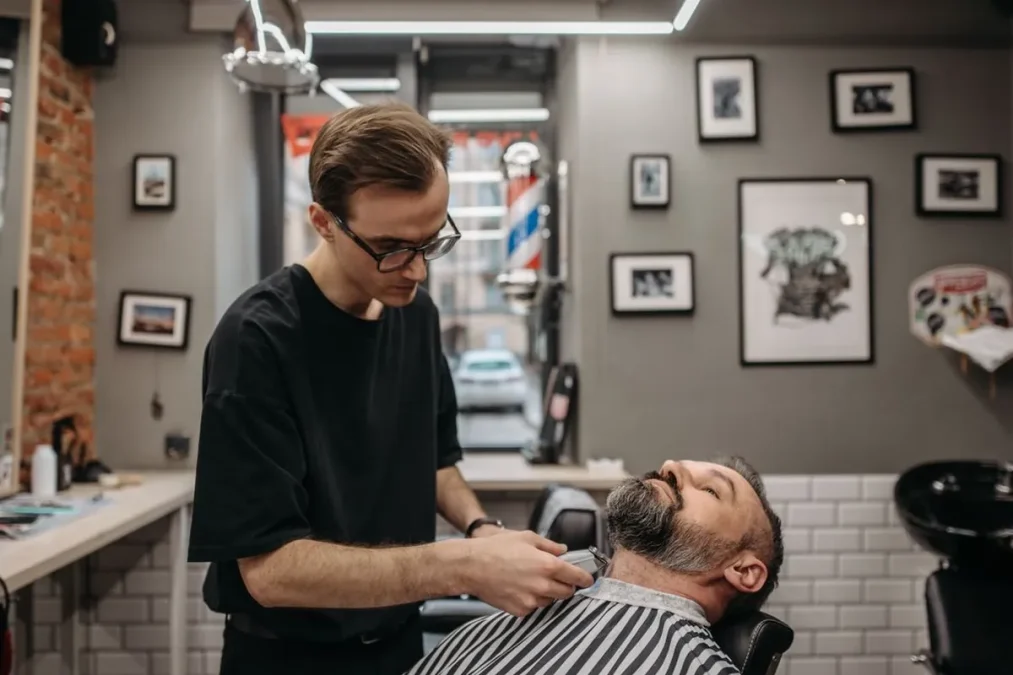 A barber working on a haircut in a barbershop.