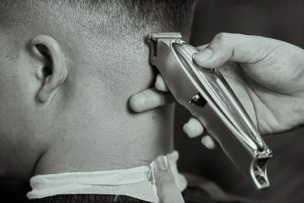 Buzz cut: a barber trimming hair with clippers.