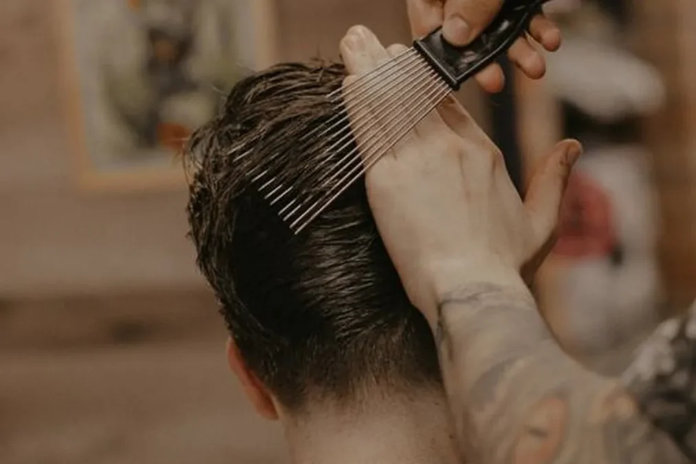 Clay: a barber combing textured hair in a barbershop.