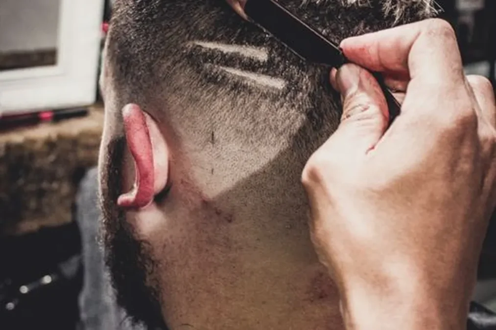 A barber detailing a haircut in a barbershop.