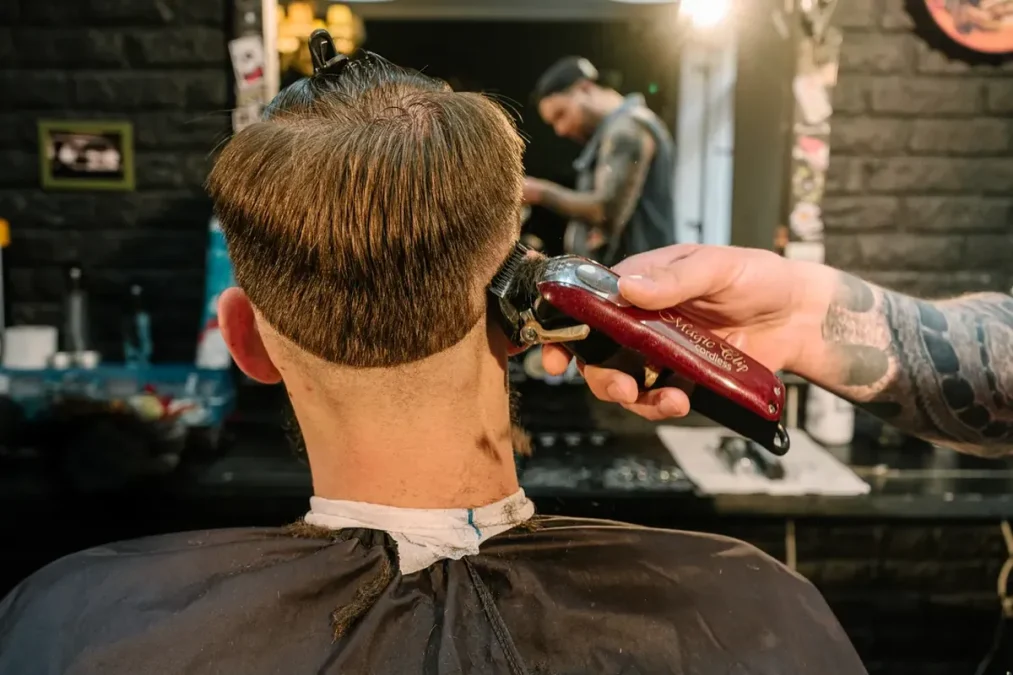 Barber tapering the nape with clippers in a barber shop